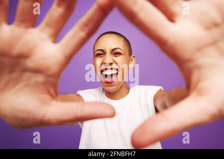 Porträt einer aufgeregten Frau mit den Händen vorne. Weibchen mit kurzer Frisur, die Kamera anschaut und lacht. Stockfoto