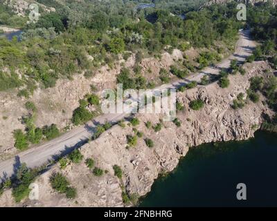 Felsige Ufer des Radon Lake an einem sonnigen Sommermorgen. Luftaufnahme eines alten überfluteten Granitsteinbruchs. Ein malerischer Teich. Stockfoto