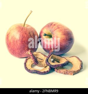 Zwei frische Äpfel und getrocknete Apfelscheiben. Lagerung von Vitaminen für den Winter und Frühling. Gesunde Ernährung. Isolierte Objekte auf weißem Hintergrund. Stockfoto