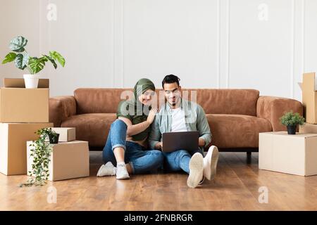 Glücklicher Mann und Frau, die nach einem Umzug einen Laptop benutzten Stockfoto