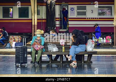 Bangkok Bahnhof - 20. März 2021: Pendler sitzen auf einer Bahnsteigesbank. Jeder trägt eine Gesichtsmask und hält seine soziale Distanz. Stockfoto