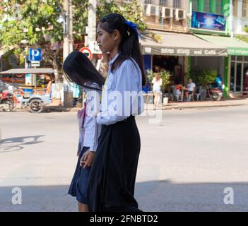 Zwei Schulmädchen, die sich die Hände halten, gehen nach Hause in Siem Reap, Kambodscha. Es gibt ein Café im Hintergrund. Leichter Bokeh-Effekt. Stockfoto