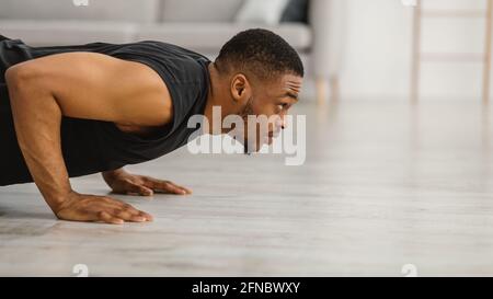 Athletic Black Guy Macht Liegestütze Training Auf Dem Boden Zu Hause Stockfoto