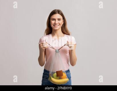 Junge Lächelnde Frau Trägt Waschbare Netz Netzstring Tasche Mit Bio-Früchte Stockfoto