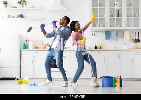 Fröhliche afroamerikanische Familie, die Spaß beim Reinigen der Küche hat Stockfoto