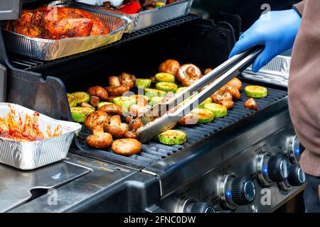 Grillen im Freien, leckere Champignons und grüne Zucchini auf dem Grill, Nahaufnahme, selektiver Fokus. Stockfoto