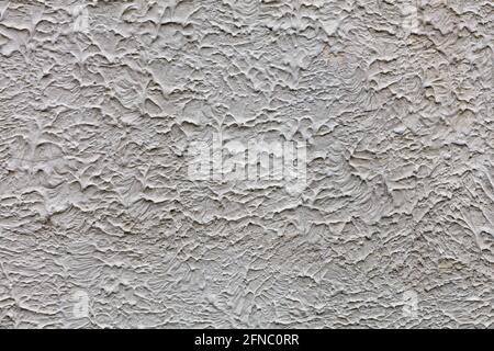 Struktur und Hintergrund einer rauen Betonwand, die mit einer ausgehärteten flüssigen Betonmischung mit Tüchern, Streifen und Rissen bedeckt ist. Stockfoto