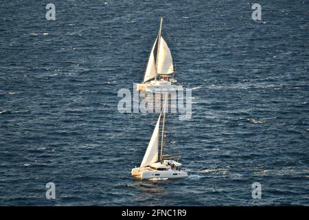 Sonnenuntergangsseerspitze mit Katamaran-Segelbooten und Crew auf den Gewässern der Insel Santorini in den Kykladen in Griechenland. Stockfoto