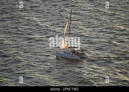 Sonnenuntergang mit einem Katamaran und einer Crew auf den Gewässern der Insel Santorini in den Kykladen in Griechenland. Stockfoto