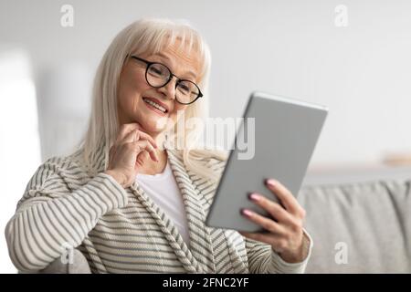 Lächelnde reife Frau mit Tablet auf der Couch sitzen Stockfoto