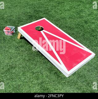 Rot-weiße Bohnenbeutel werfen Cornhole-Spiel auf einem grünen Rasen. Stockfoto