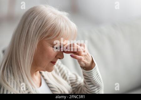 Ermüdete verärgert ältere Frau massiert Nasenrücken Stockfoto
