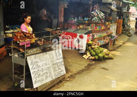 Laotischer Verkäufer Grill Braten Fleisch Huhn alkoholfreie Getränke Wasser für Verkauf laotische Menschen und ausländische Reisende in lokalen Papaya Salat Oder Som TUM Local Shop in Lou Stockfoto