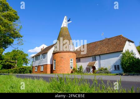 Traditionelles Kentish Oast House am Straßenrand und weißes Klappbretthaus, das jetzt in ein Haus umgewandelt wurde. Kent, England, Großbritannien Typische Kent-Landschaft Stockfoto