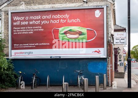 Eine Plakatwand, auf der die Menschen ermutigt werden, Gesichtsmasken in Zügen zu tragen. Bezahlt von Greater Anglia. Mill Road, Cambridge, Großbritannien Stockfoto