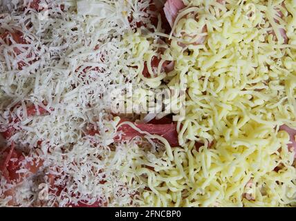 Blick von oben auf isolierte rohe hausgemachte, frisch zubereitete Pizza mit einfachen Toppings Tomatensauce, zwei geriebenen verschiedenen Sorten Pecorino und gouda Stockfoto
