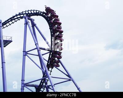 Russland, Sotschi 16.04.2021. Fragment der Attraktion Achterbahn mit Menschen, die auf ihm gegen den Wolkenhimmel reiten Stockfoto