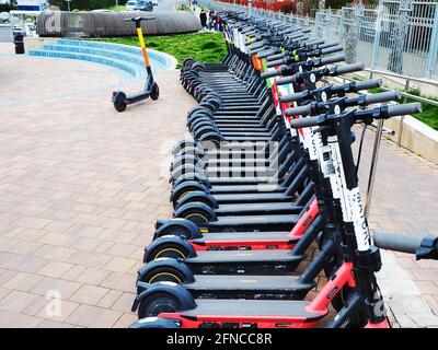 Russland, Sotschi 16.04.2021. Es gibt viele Elektro-Scooter aufgereiht in Reihe von Pflasterplatten. Motorroller-Verleih Stockfoto