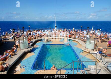 Menge von Passagieren, die am Pool auf einem sitzen Kreuzschiff in der Karibik Stockfoto