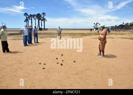 Vendrell, Spanien. Mai 2021. Eine Gruppe von Männern, die Gesichtsmasken tragen, als vorbeugende Maßnahme gegen Covid-19, spielen Petanque am Strand von Vendrell. Seit dem 9. Mai hat die Regierung das Ende des Alarmzustands in Spanien beschlossen, die Menschen kehren vor der Pandemie in den Zustand der Normalität zurück. Restaurants, Handel, Tourismus und das tägliche Leben gehen mit präventiven Maßnahmen wie dem Tragen von Masken und der Wahrung sozialer Distanzierung weiter. Kredit: SOPA Images Limited/Alamy Live Nachrichten Stockfoto