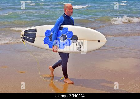 Vendrell, Spanien. Mai 2021. Am Strand von Vendrell kommt ein Surfer aus dem Wasser. Seit dem 9. Mai hat die Regierung das Ende des Alarmzustands in Spanien beschlossen, die Menschen kehren vor der Pandemie in den Zustand der Normalität zurück. Restaurants, Handel, Tourismus und das tägliche Leben gehen mit präventiven Maßnahmen wie dem Tragen von Masken und der Wahrung sozialer Distanzierung weiter. Kredit: SOPA Images Limited/Alamy Live Nachrichten Stockfoto