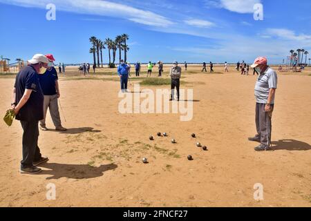 Vendrell, Spanien. Mai 2021. Eine Gruppe von Männern, die eine Gesichtsmask als vorbeugende Maßnahme gegen Covid-19 tragen, spielen Petanque am Strand von Vendrell seit dem 9. Mai hat die Regierung das Ende des Alarmzustands in Spanien verhängt, die Menschen kehren vor der Pandemie in den Zustand der Normalität zurück. Restaurants, Handel, Tourismus und das tägliche Leben gehen mit präventiven Maßnahmen wie dem Tragen von Masken und der Wahrung sozialer Distanzierung weiter. Kredit: SOPA Images Limited/Alamy Live Nachrichten Stockfoto