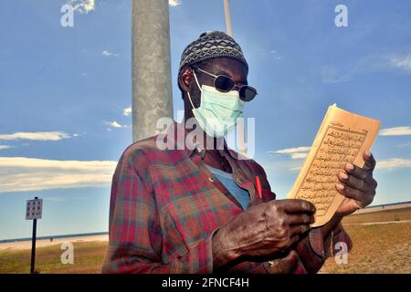 Vendrell, Spanien. Mai 2021. Ein muslimischer Mann mit Gesichtsmaske als vorbeugende Maßnahme gegen Covid-19 liest einige Verse aus dem Koran in Vendrell seit dem 9. Mai hat die Regierung das Ende des Alarmzustands in Spanien angeordnet, die Menschen kehren vor der Pandemie in den Zustand der Normalität zurück. Restaurants, Handel, Tourismus und das tägliche Leben gehen mit präventiven Maßnahmen wie dem Tragen von Masken und der Wahrung sozialer Distanzierung weiter. Kredit: SOPA Images Limited/Alamy Live Nachrichten Stockfoto