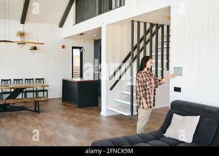Junge Frau, die zu Hause auf die Sicherheitstafel oder den Bildschirm schaut Wohnzimmer Stockfoto
