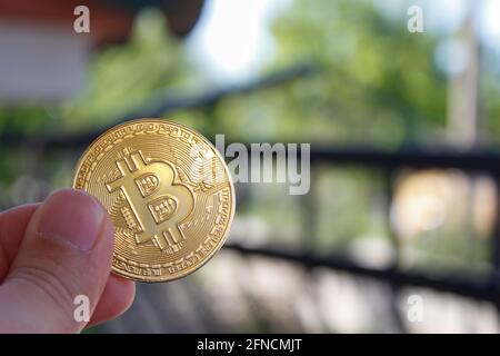 Nahaufnahme einer virtuellen Bitcoin-Münze in der Hand. Mann Hand hält goldene BTC Münze. Bitcoin ist eine beliebte Kryptowährung. Stockfoto