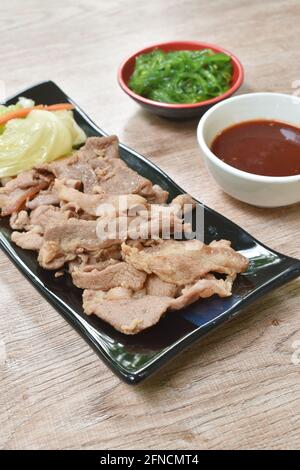 Koreanisch gebratenes Schweinefleisch in Scheiben mit Kohl auf Tellersoße Und Algen in Sesamölsalat Stockfoto