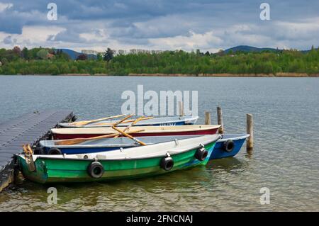 Verankerte Ruderboote auf einem Steg auf einem See mit Landschaftlich schöne Aussicht auf Berge und Wolken im Hintergrund Stockfoto