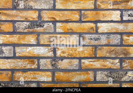 Hintergrund und Textur der Wand aus gelb-braunem altem Ziegel mit breiten grauen Zementgelenken. Hohe Auflösung, Nahaufnahme. Stockfoto