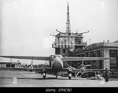 Altes Schwarz-Weiß-Foto mit einem Imperial Airways De Havilland DH.86 Express, Registrierung G-ACPL und dem Namen 'Delphinus', auf dem Croydon Airport, London, in den 1930er Jahren. Der Kontrollturm des Flughafens dahinter. Stockfoto