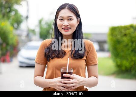 Frau trinkt Eiscola im Glas. Glas Cola, Softdrinks mit Eis, Speisen- und Getränkekonzept. Stockfoto