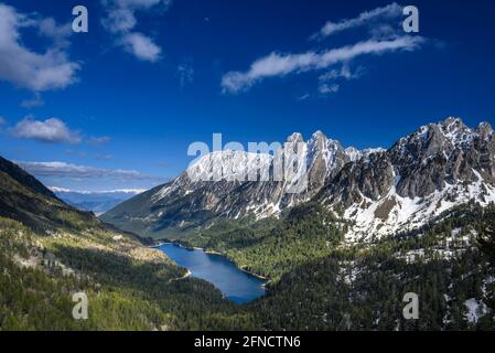 Encantats Twin Peaks und der Estany de Sant Maurici See vom Mirador del Estany aus gesehen, der an einem Frühlingsnachmittag (Aiguestortes, Pyrenäen) aufschlägt Stockfoto