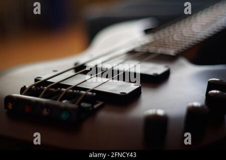 Nahaufnahme eines glatten Körpers, Tonabnehmer, Steg, Knöpfe und Saiten eines Bassgitarren-Musikinstruments mit Hintergrundbeleuchtung Stockfoto