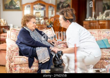 KRANKENSCHWESTER, DIE MIT ÄLTEREN MENSCHEN SPRICHT Stockfoto