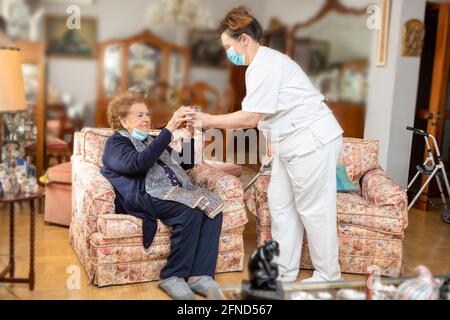 KRANKENSCHWESTER, DIE ÄLTEREN MENSCHEN EIN GLAS WASSER GIBT Stockfoto