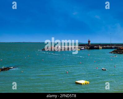 Blick auf einen Hafen mit einem Leuchtturm am Pier an der irischen Ostküste. Stockfoto