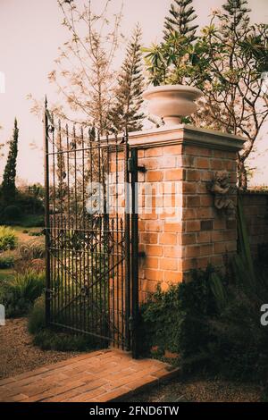 Alter Garten gusseisernes Stahltor auf Steinsäulenbogen Eingangswand Stockfoto