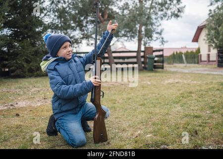 Kleiner Junge, der das Luftgewehr beladen hat Stockfoto