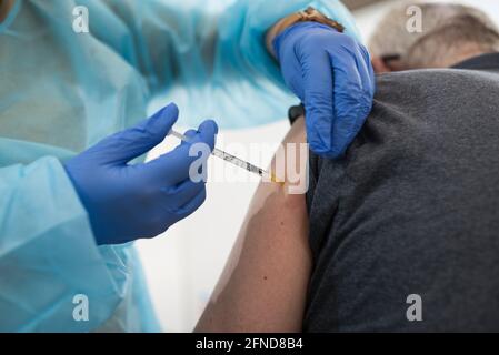 Die Hände eines Arztes impfen gegen Covid-19 ein Mann im Arm. Stockfoto