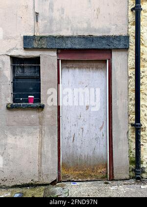 Das Fenster war mit einer schwarzen, schwarz lackierten Einweg-Kaffeetasse verkleidet Fensterleiste und Holztür Stockfoto