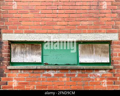 Drei vernagelte Fenster in einer roten Backsteinmauer Stockfoto