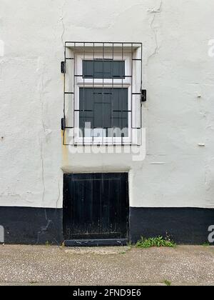 Fenster hinter Metallgrill und blockierte hölzerne Tür im Keller Ebenerdreich Stockfoto