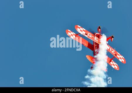 Pitts Spezial-Kunstflugflugzeug, das steil in einen strahlend blauen Himmel klettert. Pitts S-2S führt Kunstflug auf einer Flugshow durch. Luftanzeige Stunt. Rauch Stockfoto