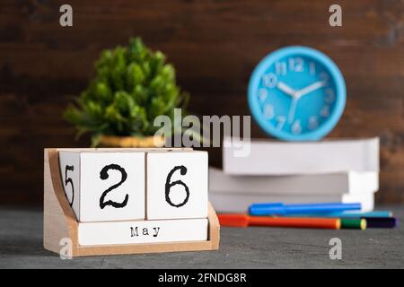 Mai. Mai 26 Holzwürfelkalender mit unscharfen Objekten auf dem Hintergrund. Stockfoto