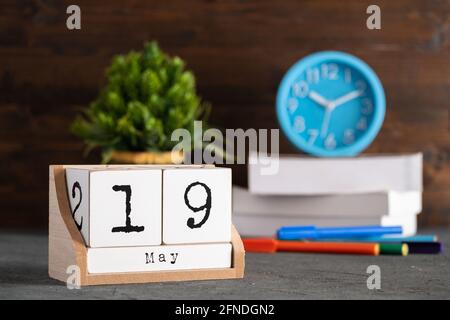 Mai. Mai 19 Holzwürfelkalender mit unscharfen Objekten auf dem Hintergrund. Stockfoto
