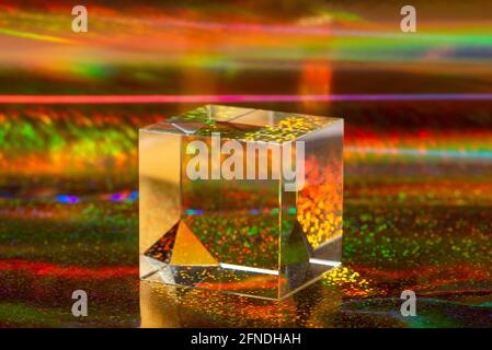 Glaswürfel auf abstraktem holographischem Hintergrund in Nahaufnahme. Helle, lebendige Abstraktion Stockfoto