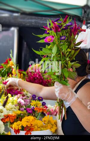 Frau, die am Stand arbeitet, um auf dem Bauernmarkt Boquet zusammenzusetzen Stockfoto